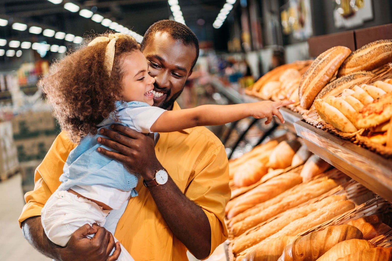 jouer-avec-son-enfant-faire-les-courses-en-s-amusant : jouer avec son enfant : un papa et sa fille choisissent du pain à l’épicerie